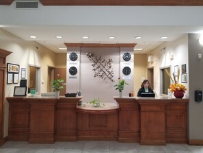 A reception desk with clocks displaying times for New York, Toronto, and Vancouver. - Merit Hotel & Suites (Fort McMurray)