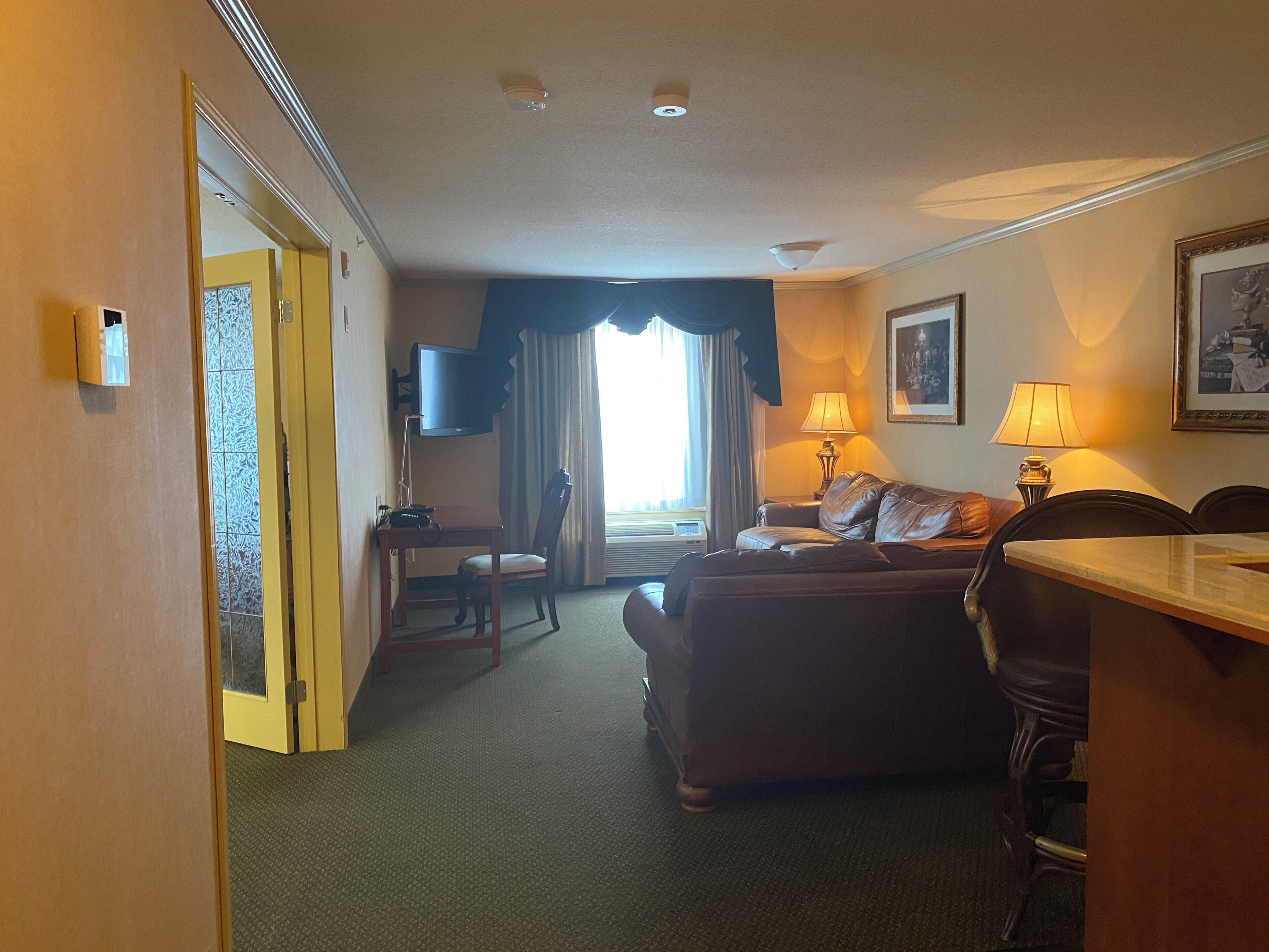 Habitación de hotel con sofá, una mesita, televisión y lámpara.