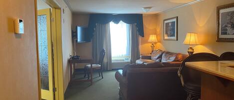Habitación de hotel con sofá, una mesita, televisión y lámpara.
