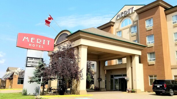 A hotel with a prominent 'MERIT HOTEL' sign, a flag, and a building entrance.