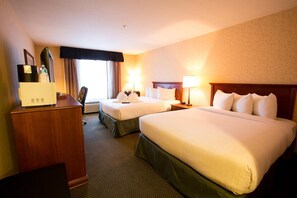 A hotel room with two beds, a desk, a chair, and a large window. - Merit Hotel & Suites (Fort McMurray)