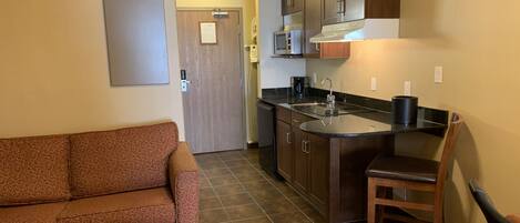 A compact living space with a kitchenette, a sofa, and a dining area.