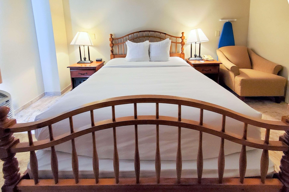 Een hotelkamer met een bed, twee nachtkastjes, een stoel en een lamp.