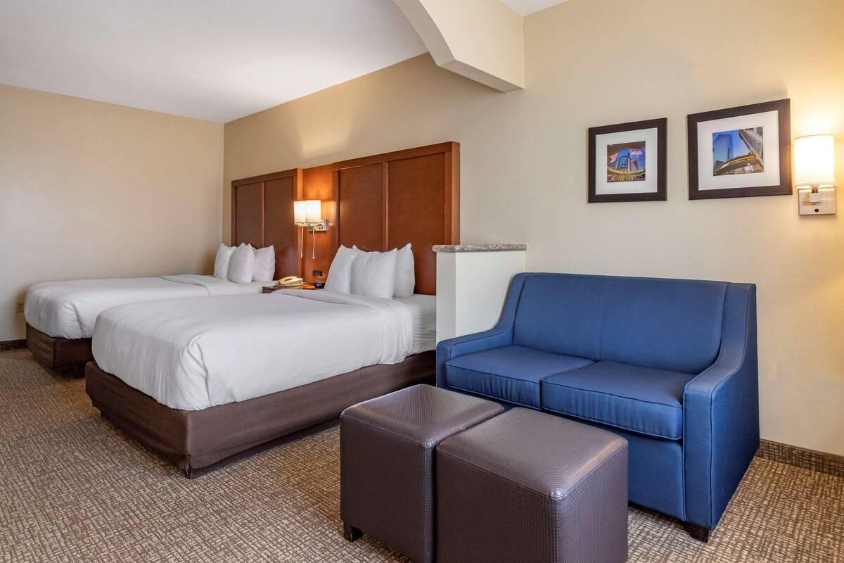 Een hotelkamer met twee bedden, een blauwe bank en een kleine tafel.