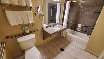 A bathroom with a toilet, sink, mirror, and shower.