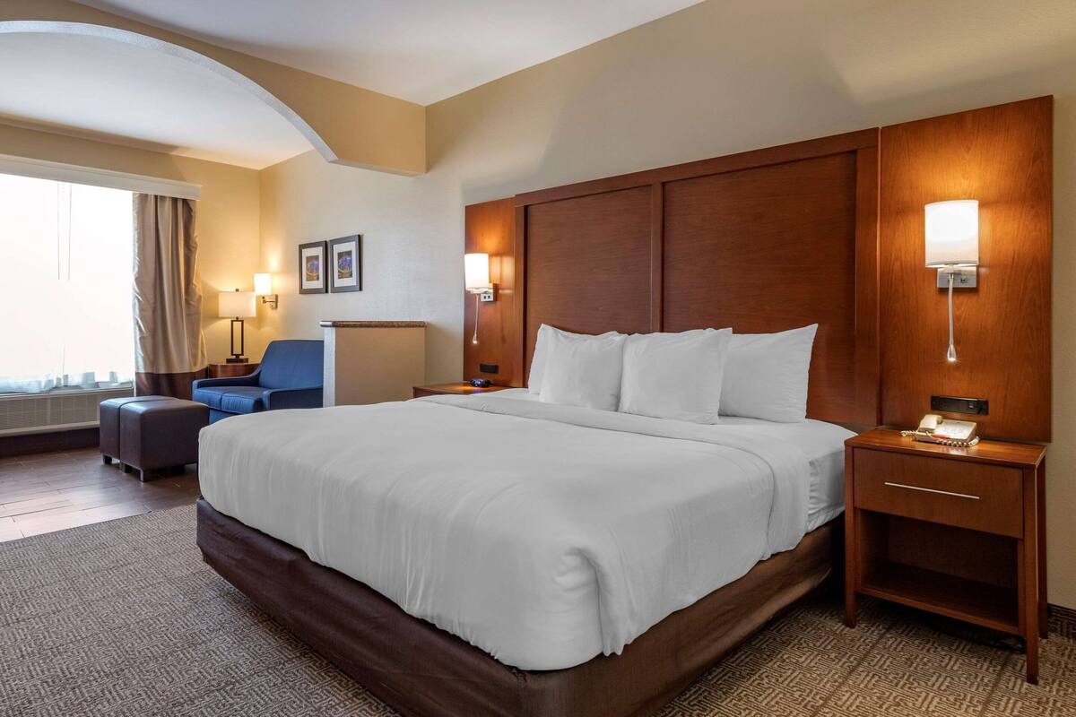 Een hotelkamer met een groot bed, een bureau, een stoel en een raam met gordijnen.