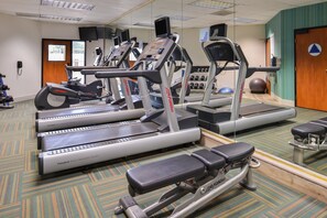 A gym with multiple treadmills, a bench press, and a mirrored wall.