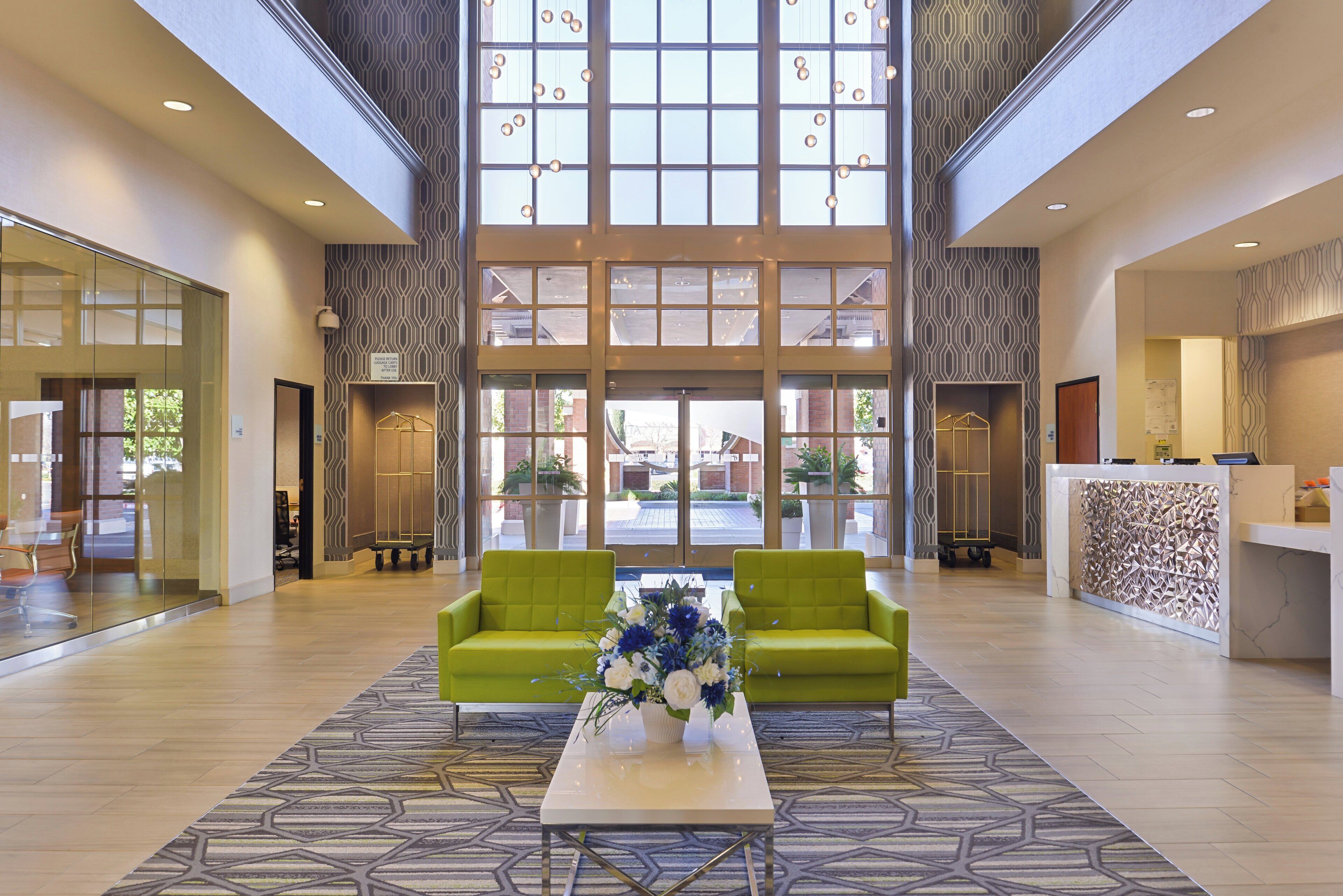 A spacious lobby with a high ceiling, large windows, and a reception desk.