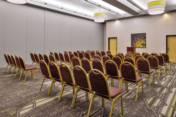 Un salón de conferencias con filas de sillas, un atril y una puerta.