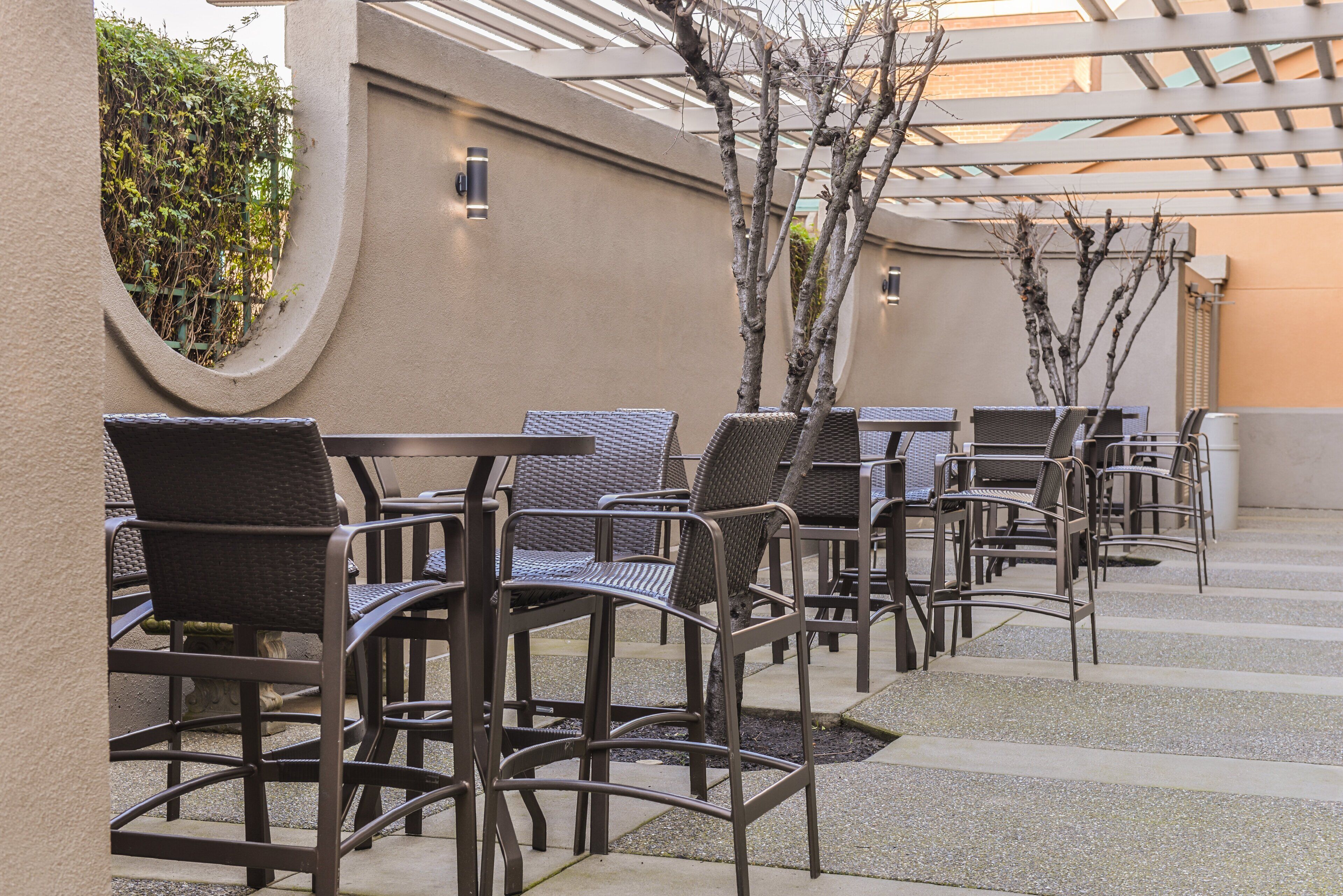 Outdoor seating with wicker chairs and tables, arranged in rows.