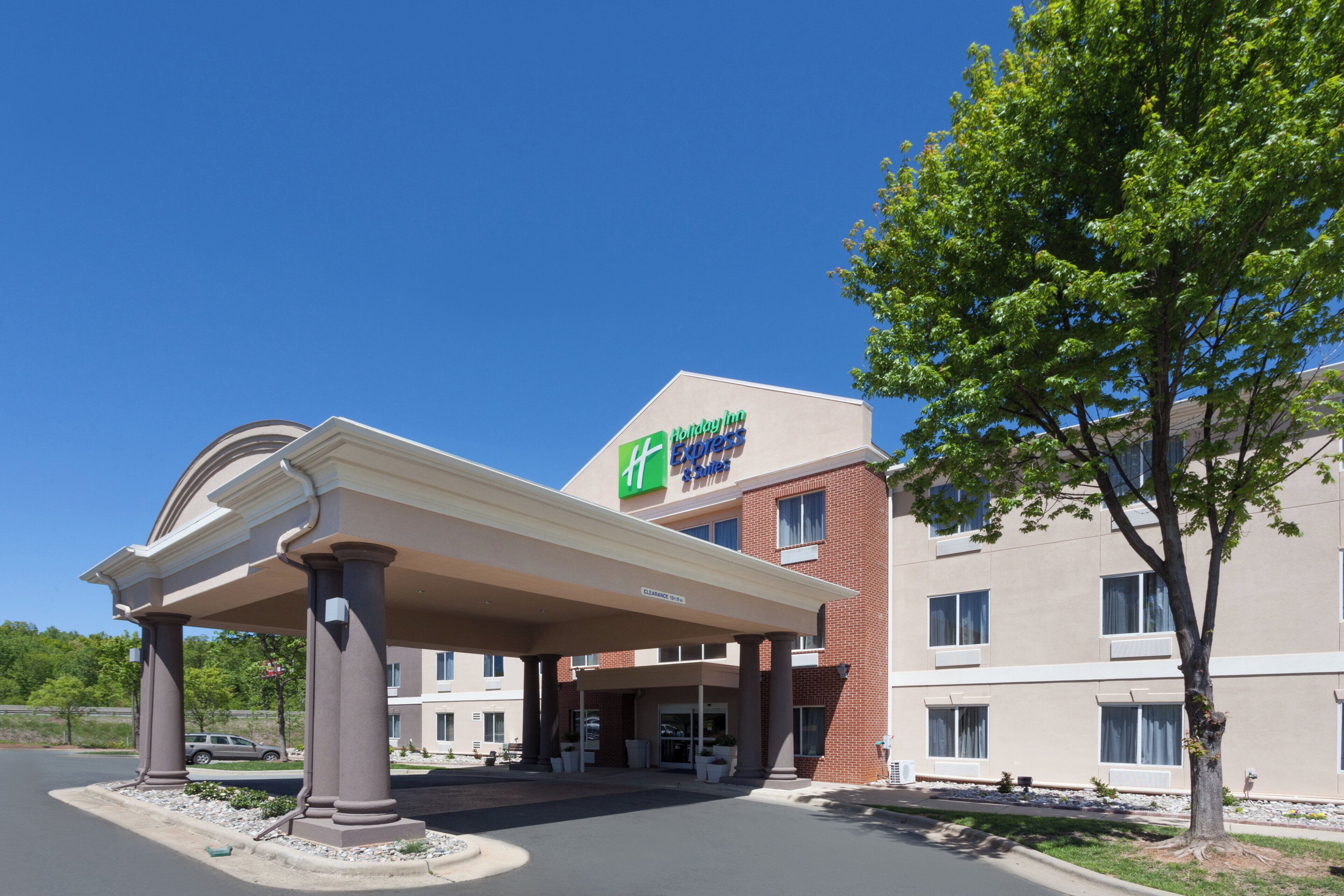 A Holiday Inn Express hotel with a covered entrance, brick facade, and a clear blue sky.