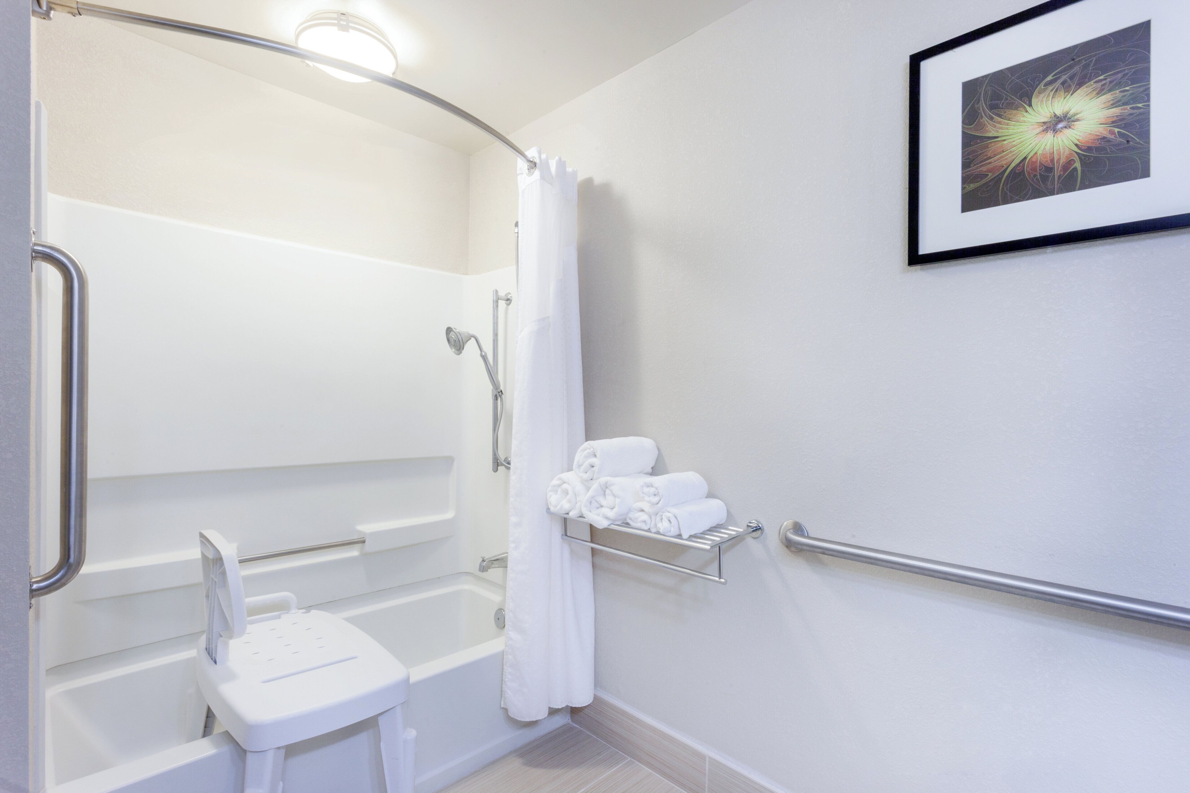 A bathroom with a shower, toilet, and a towel rack with towels.