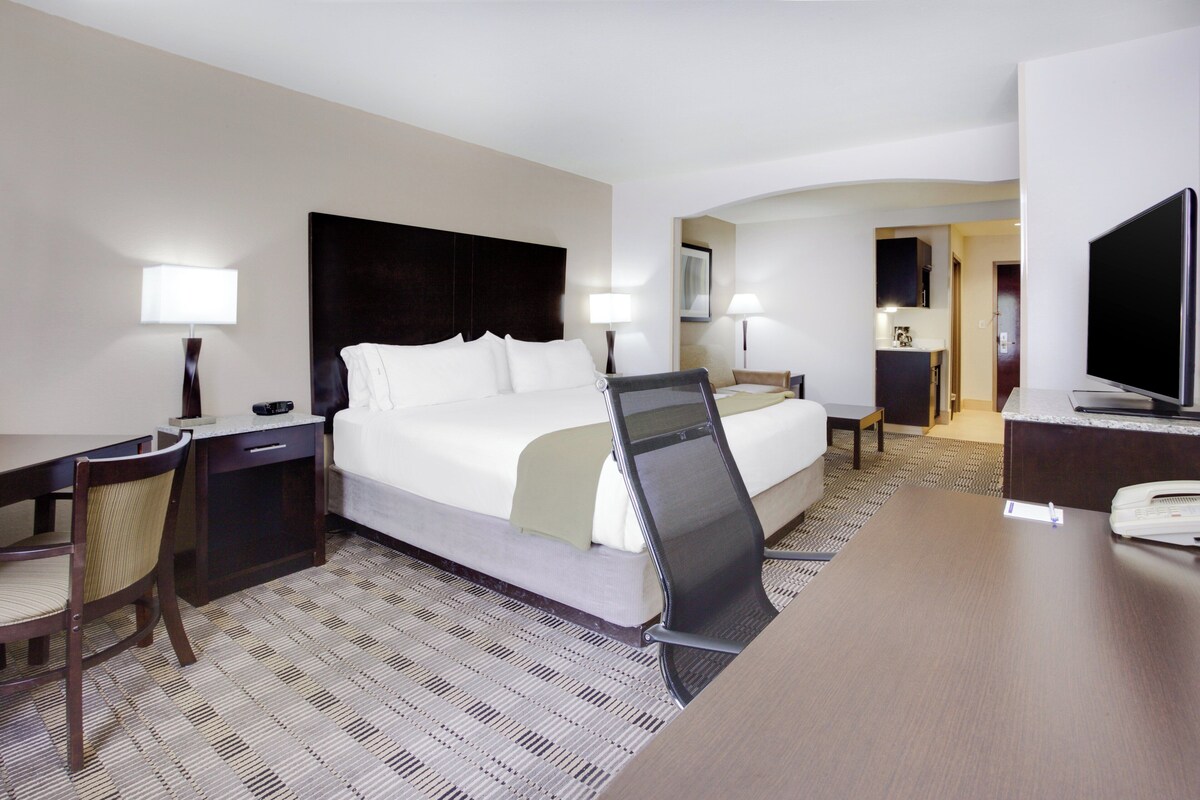 Ein Hotelzimmer mit Bett, Schreibtisch, Stuhl und Fernseher.
