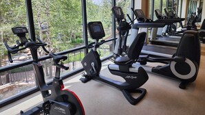 Een fitnessruimte met cardioapparatuur, een loopband en een spiegelwand.