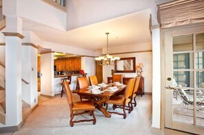 A dining area with a large wooden table, chairs, and a chandelier. - Park Plaza Beaver Creek (Avon)
