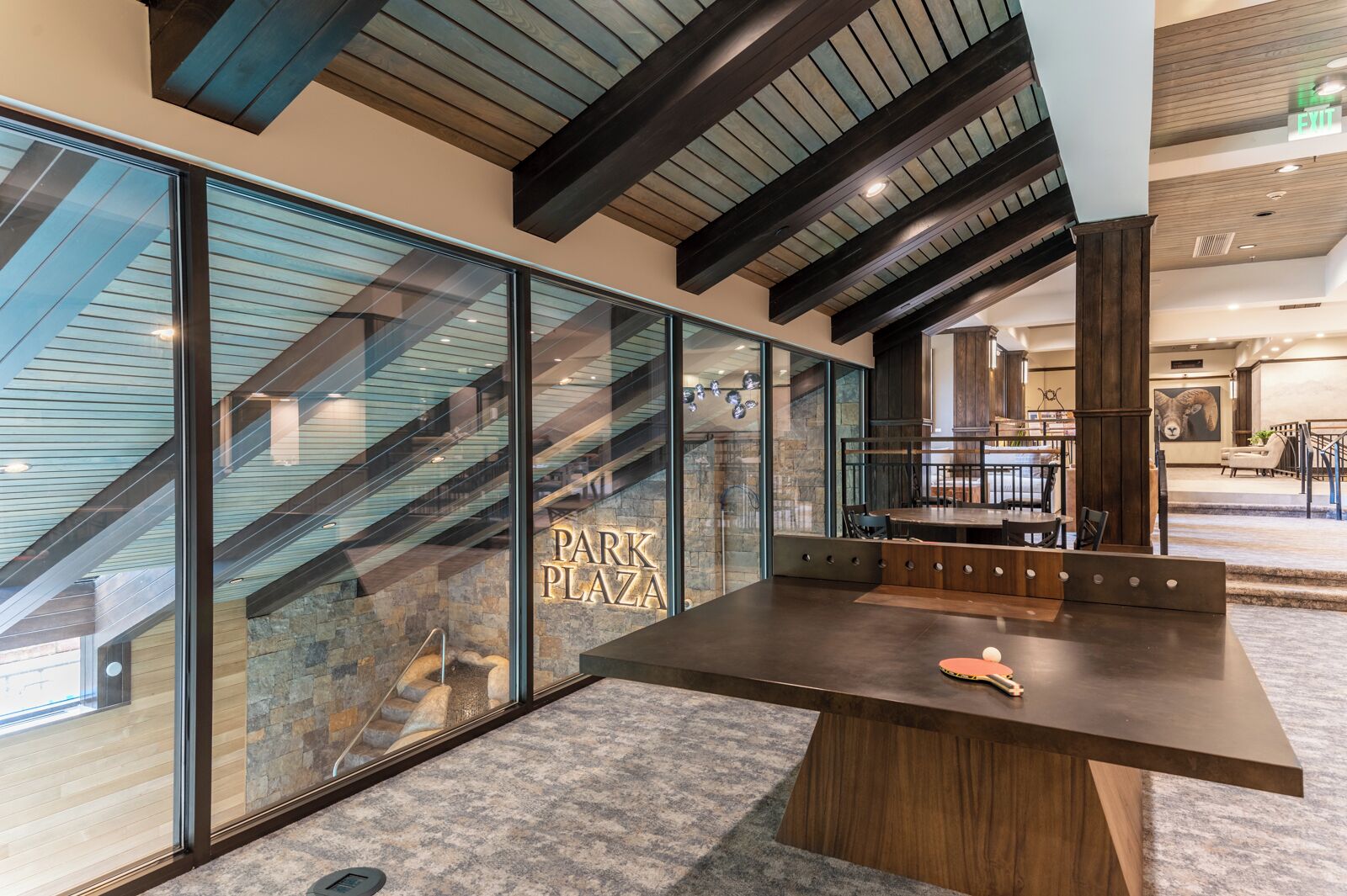 A modern interior with a large table, a staircase, and a sign reading "PARK PLAZA".