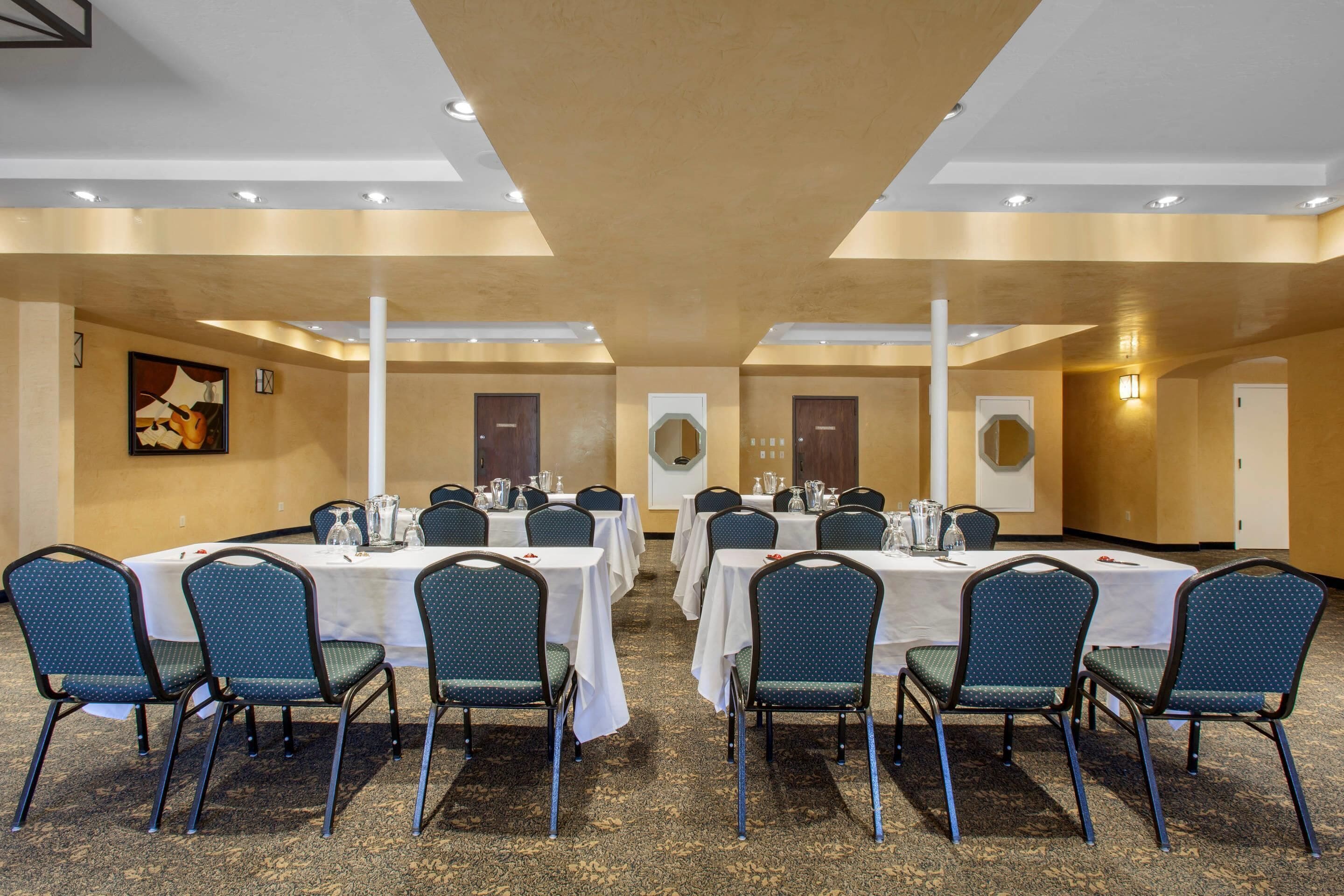 A conference room with tables and chairs, a carpeted floor, and a painting on the wall.