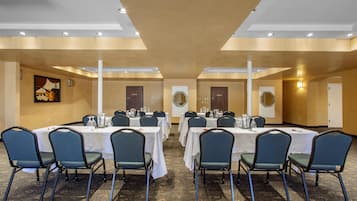 A conference room with tables and chairs, a carpeted floor, and a painting on the wall.