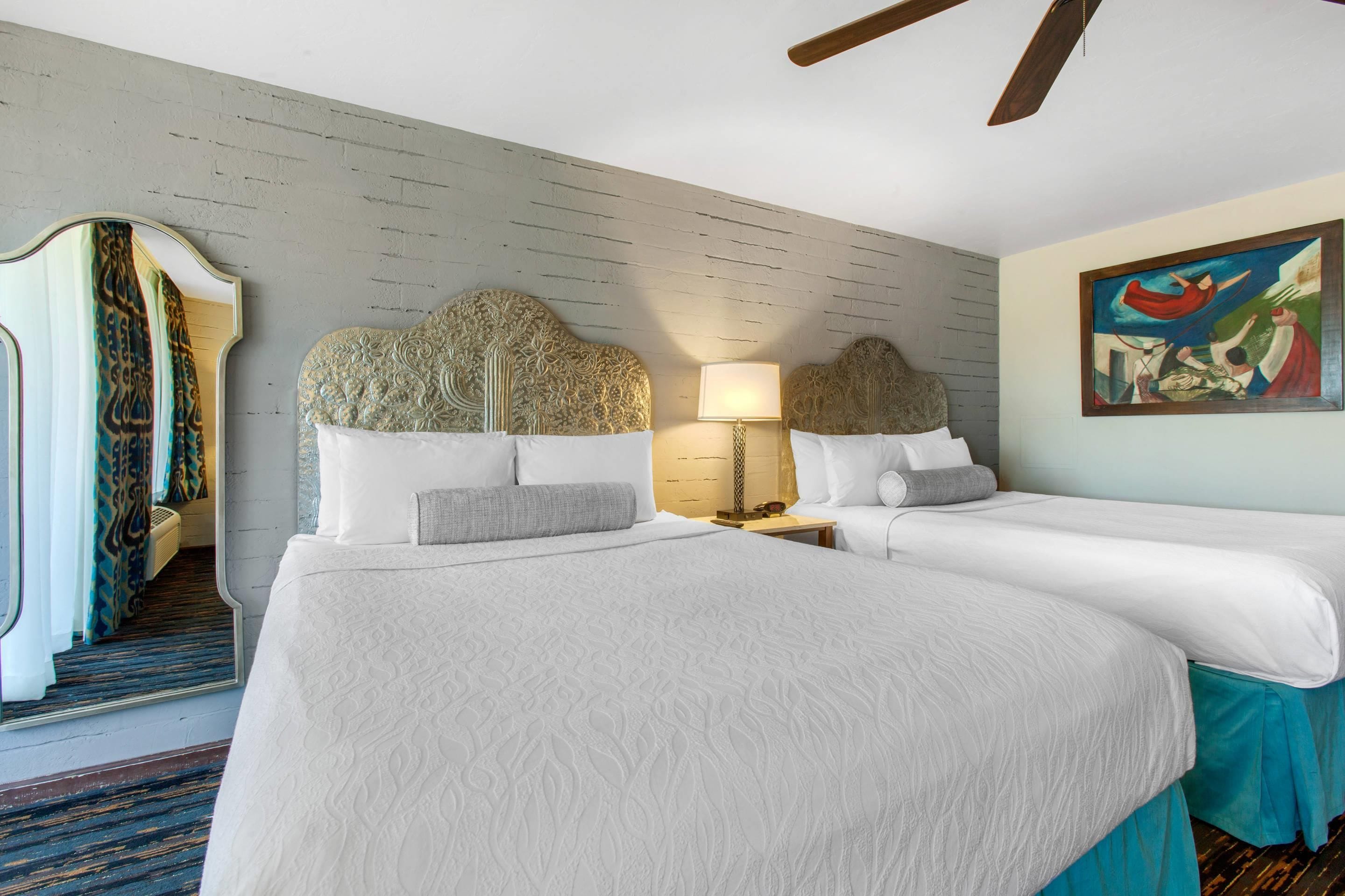 Habitación de hotel con dos camas, un cuadro grande y un diseño de cabecera original.