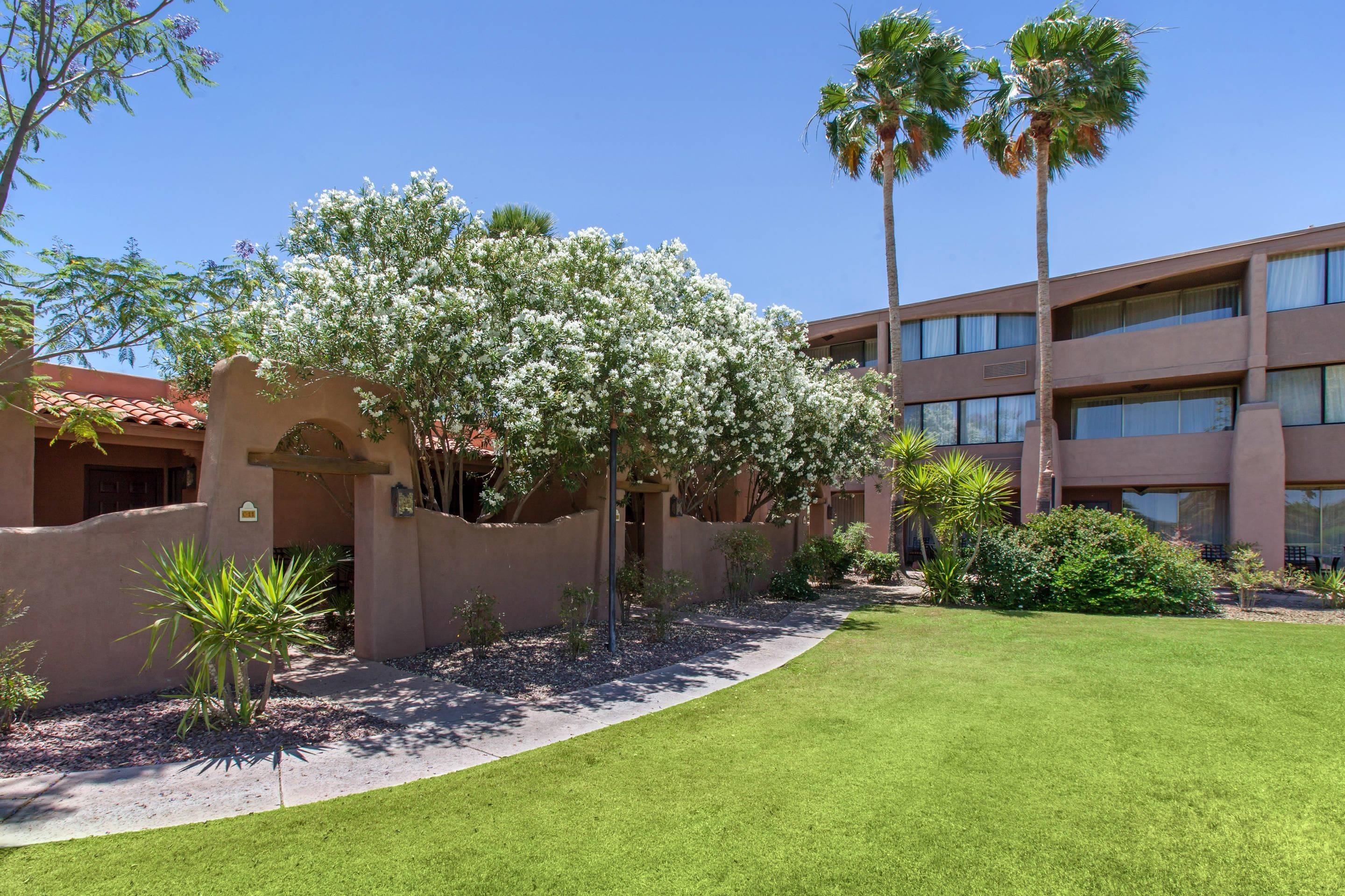 A building with a stucco exterior, a covered patio area, and a well-maintained lawn.