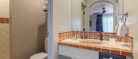 A bathroom with a toilet, a sink with a mirror, and a shower area.
