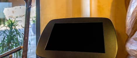 A tablet on a stand in a room with a wooden floor and a window.