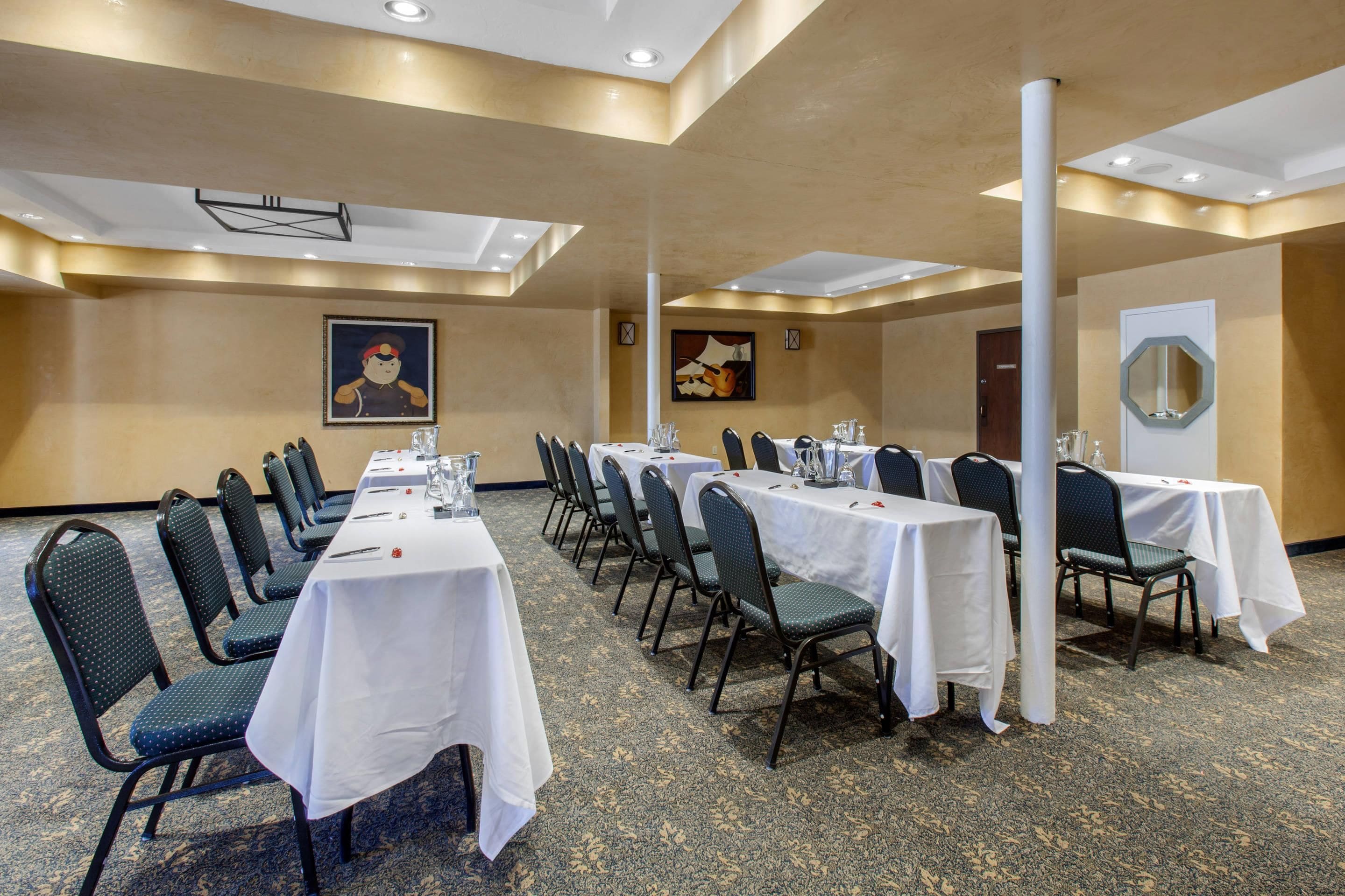 Un salón de conferencias con varias mesas y sillas, un reloj y una puerta.