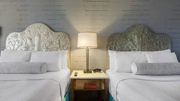A hotel room with two beds, a nightstand with a lamp, and a clock.