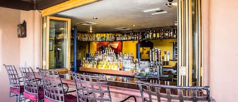 A bar area with multiple chairs and a bar counter stocked with bottles.