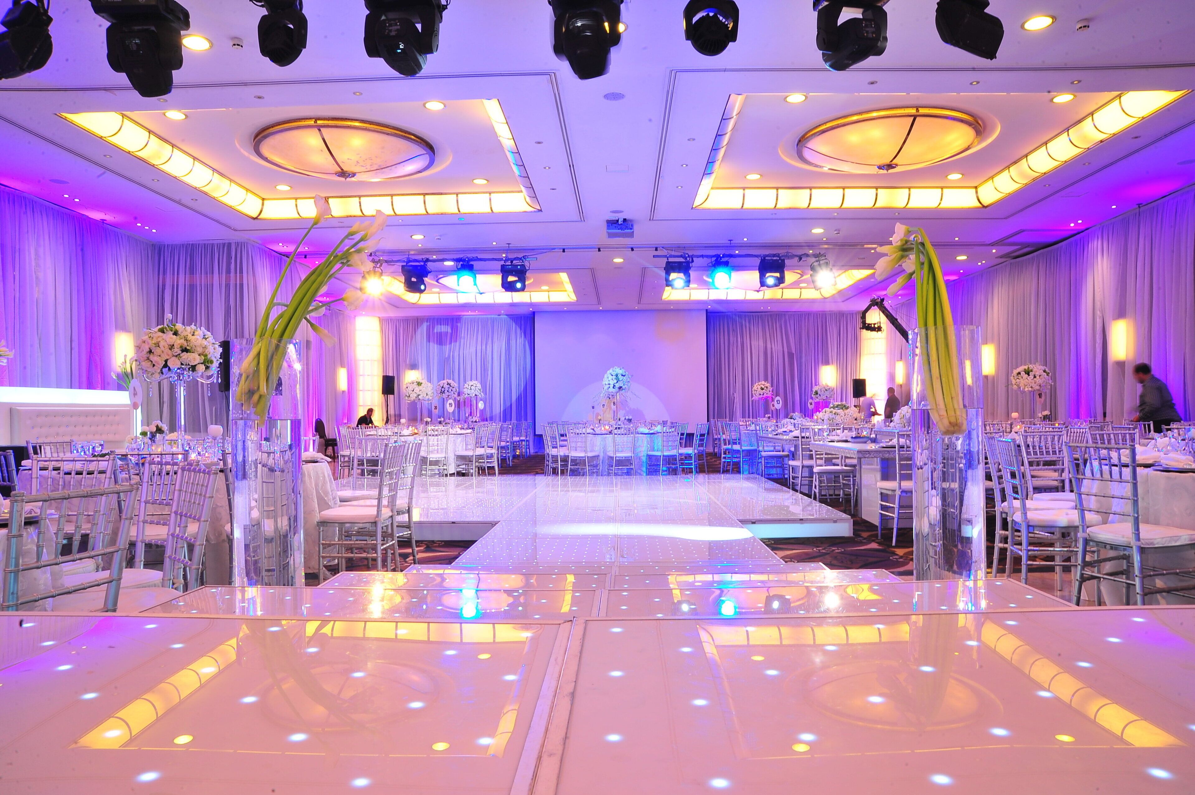 Une salle de banquet avec des tables rondes, des chaises et une piste de danse centrale.