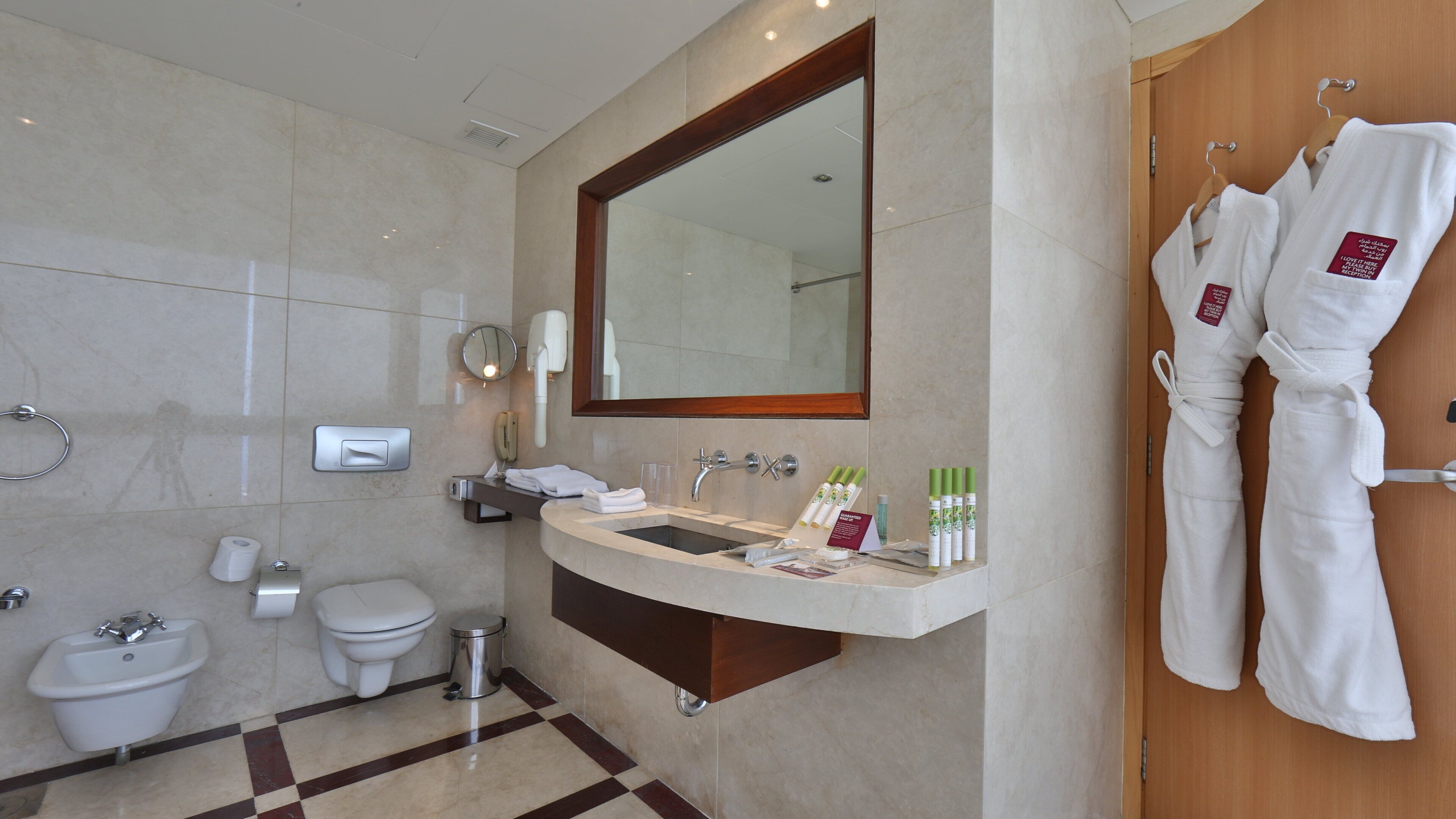 A modern bathroom with a sink, mirror, towel rack, and a toilet.