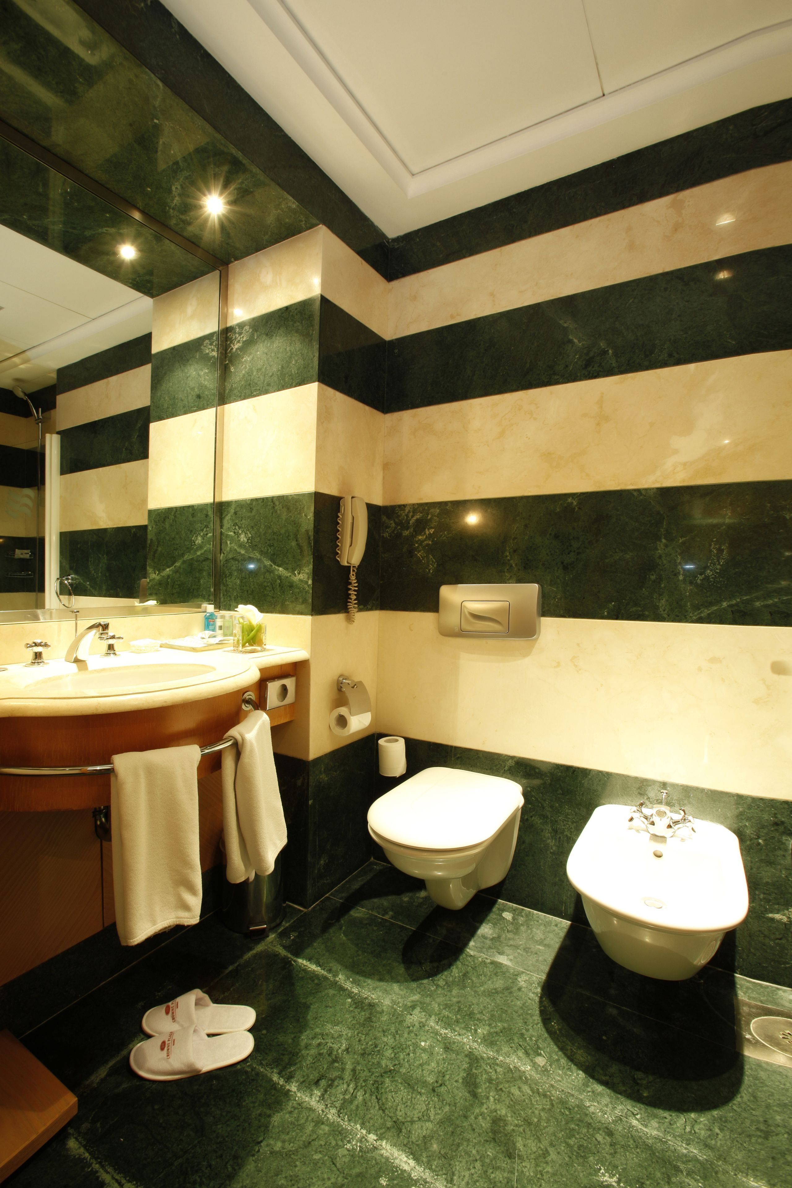 Un baño con piso de mármol, lavamanos, inodoro y bidé.