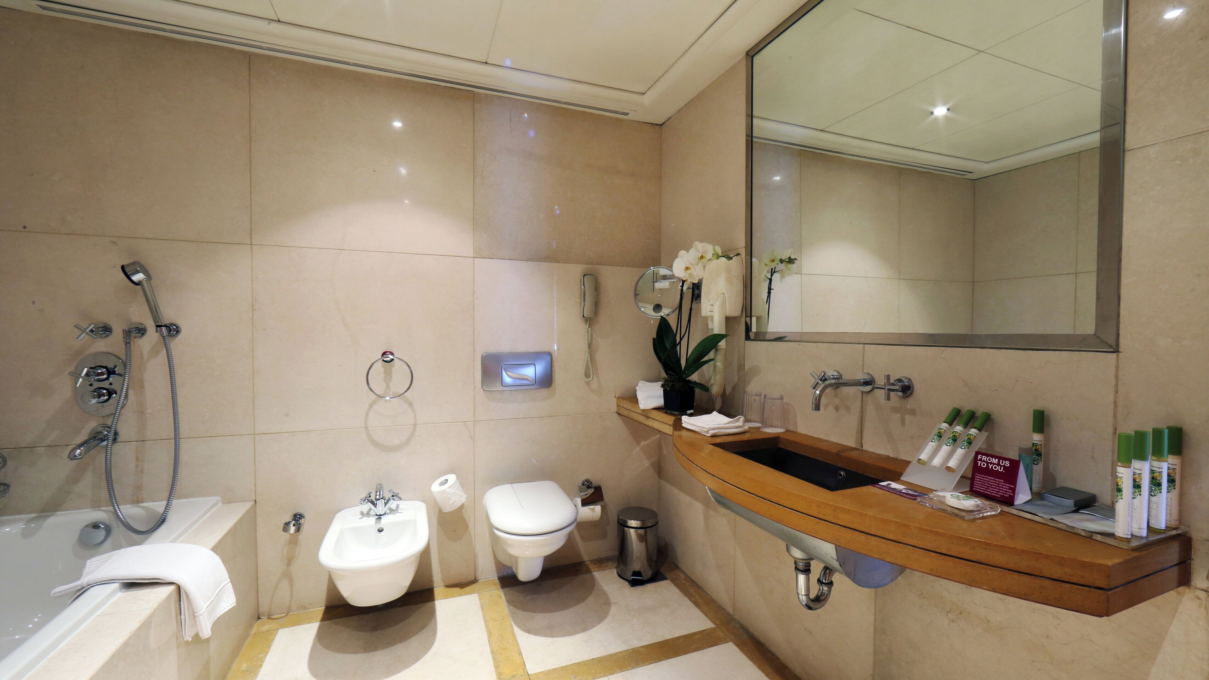 Un baño con bañera, lavamanos, inodoro y espejo.