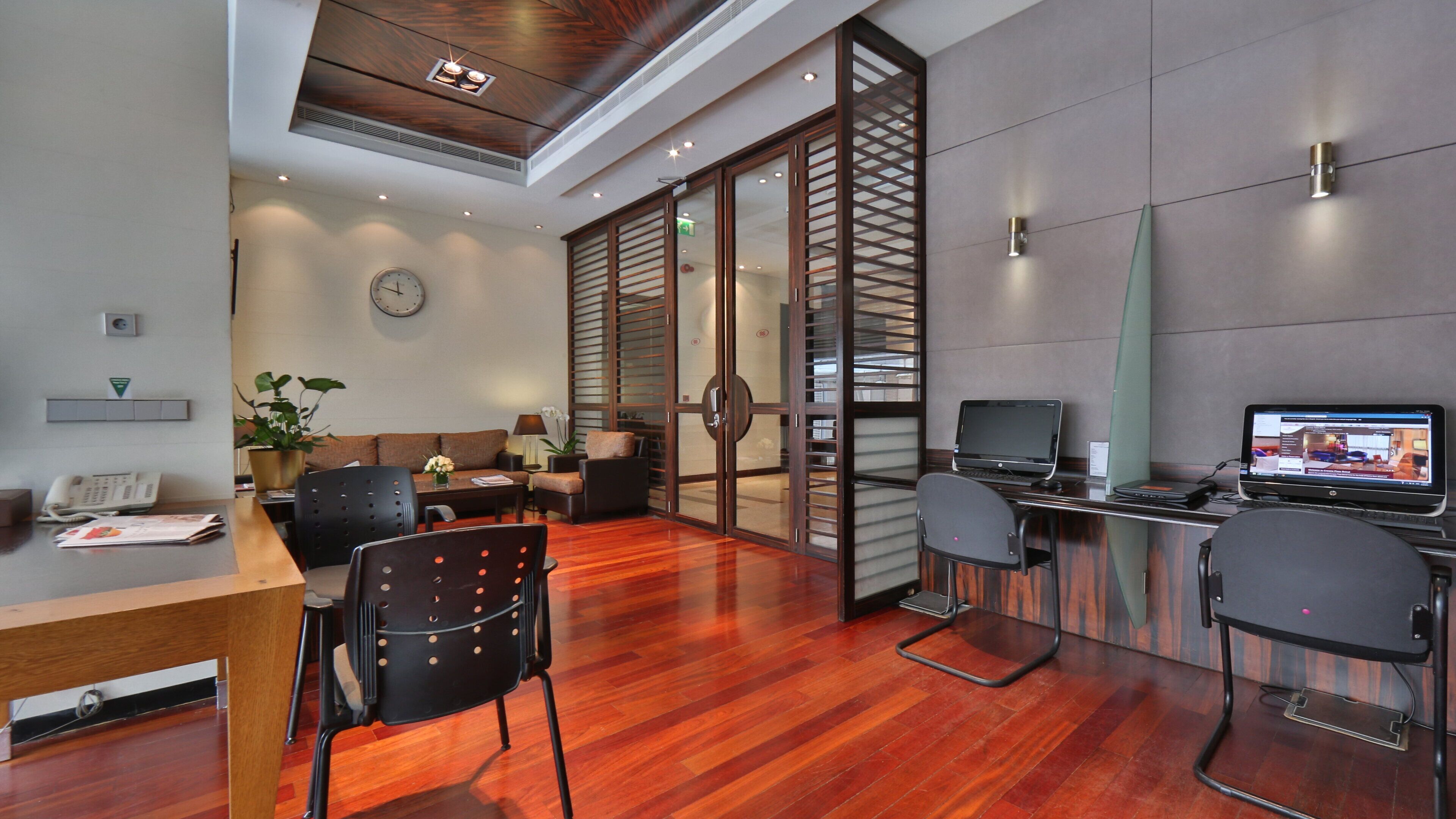 A modern office space with a reception desk, seating area, and two laptops on a desk.
