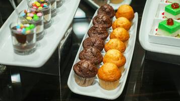 Verschiedene Desserts auf Tabletts, darunter Cupcakes und kleine Gläser mit Süßigkeiten.