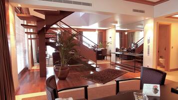 Un amplio vestíbulo de hotel con una escalera de madera, un comedor y una recepción.