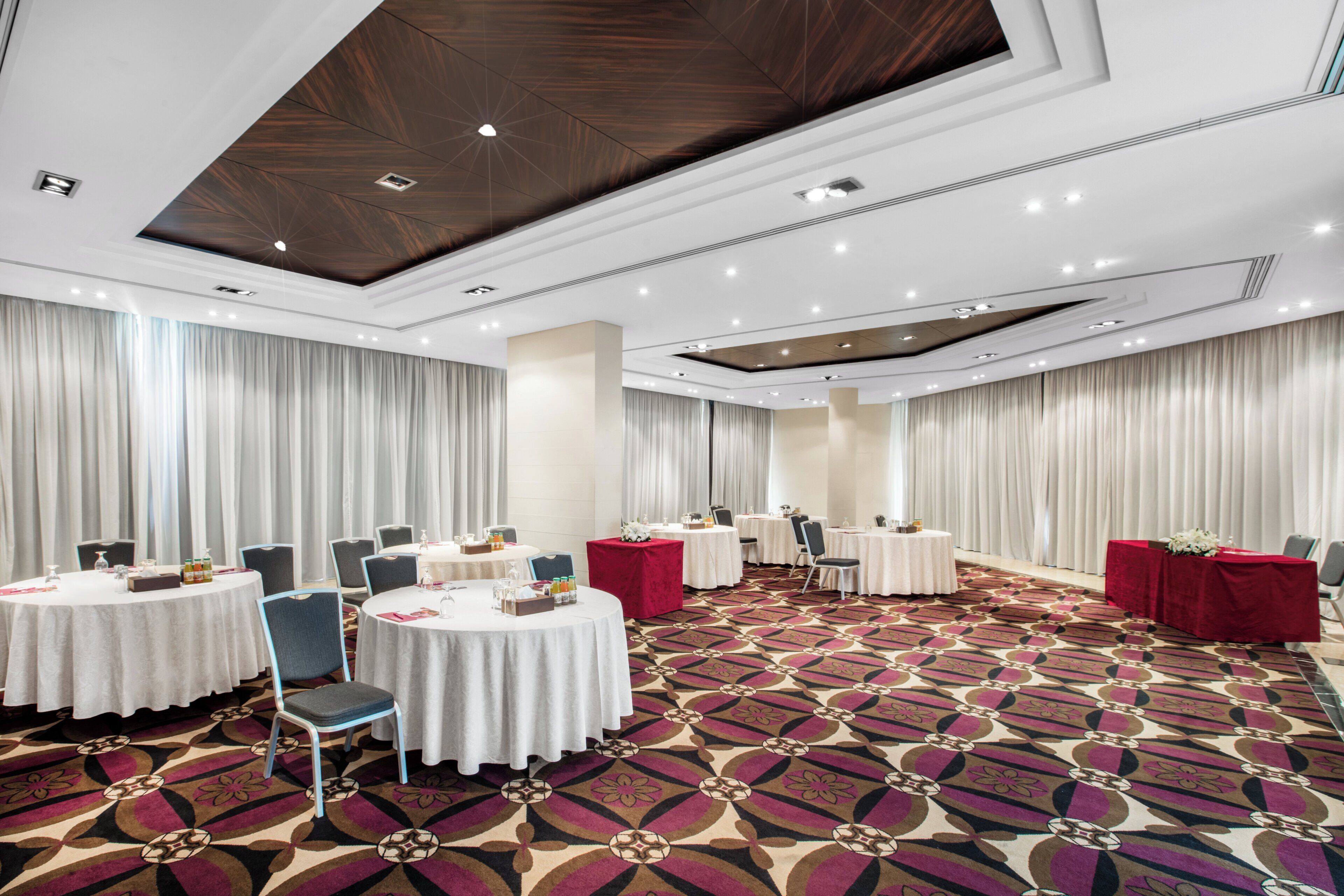 A conference room with round tables, chairs, and a patterned carpet.