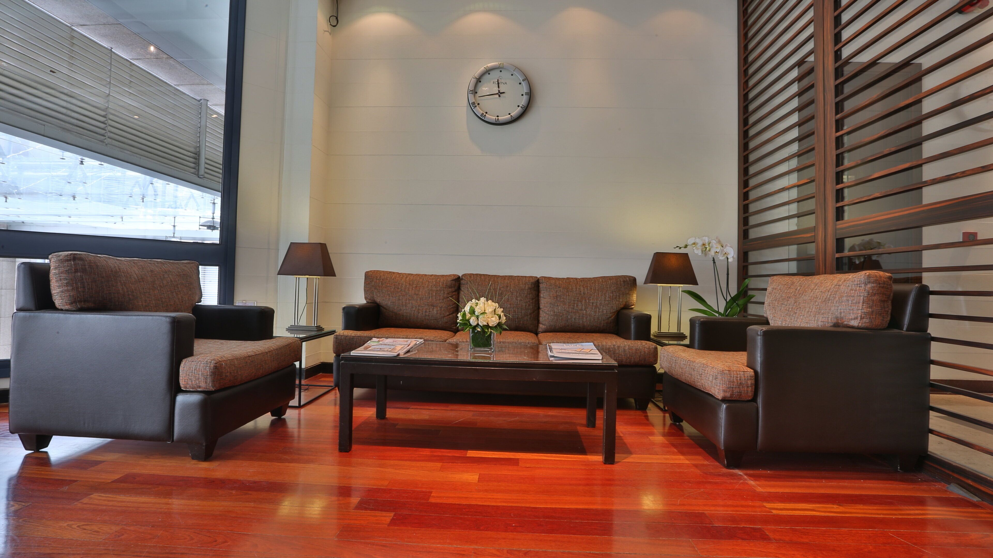 A modern lounge area with a sofa set, a coffee table, and a wall clock.