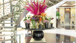 A lobby with a glass table displaying various potted plants and flowers. - Crowne Plaza Hotel Beirut by IHG (Beirut)