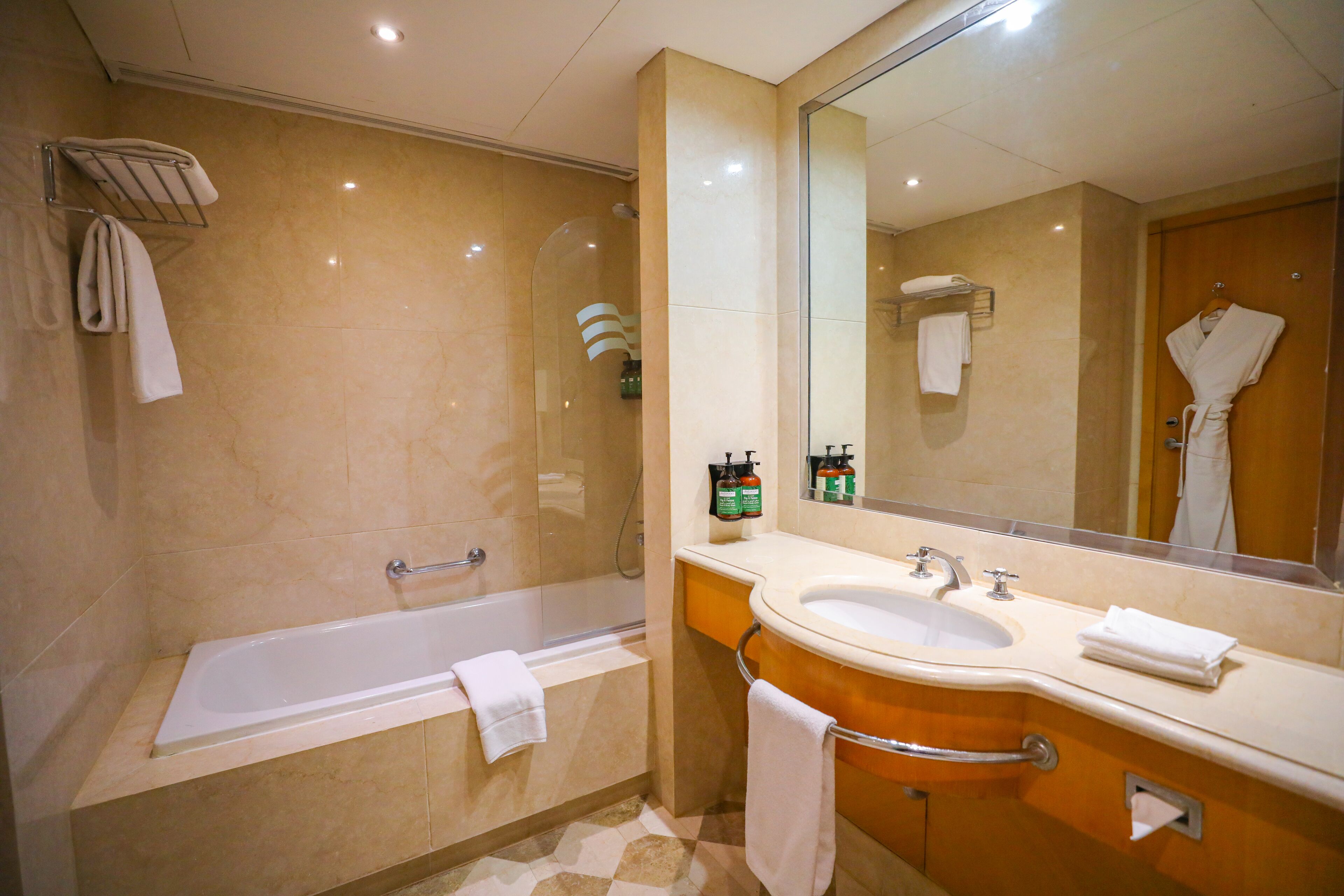 Un baño moderno con bañera, lavamanos y un espejo grande.
