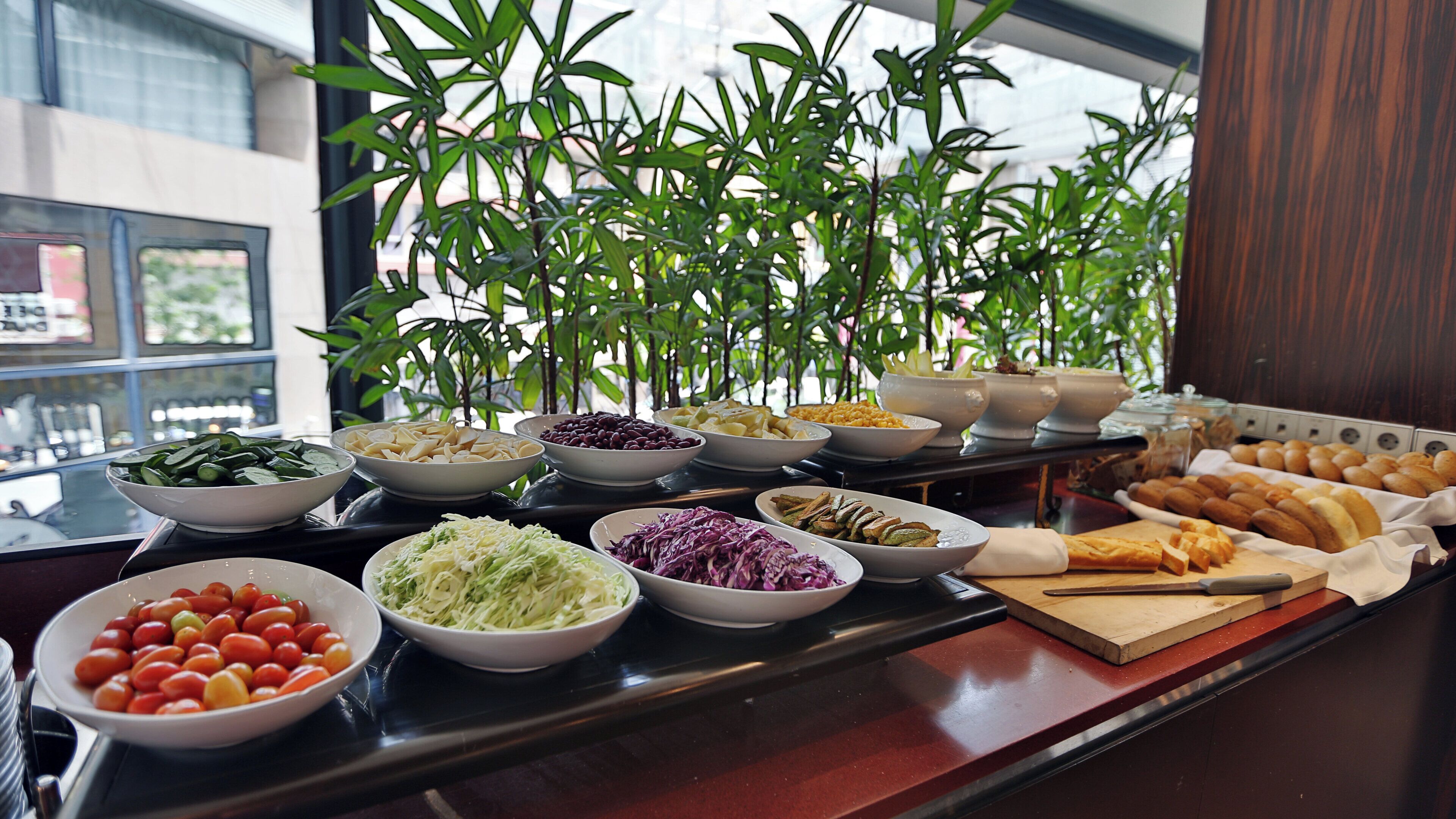 A buffet table with various food items and a potted plant in the background.