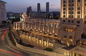 A hotel with a covered outdoor area, multiple floors, and a view of the city skyline. - Four Seasons Hotel Amman (Amman)