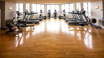 Ein Fitnessraum mit mehreren Laufbändern, Ergometer und Crosstrainern, die in Reihen angeordnet sind.