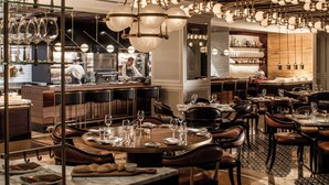 A restaurant interior with multiple dining tables, chairs, and hanging light fixtures. - Four Seasons Hotel Amman (Amman)