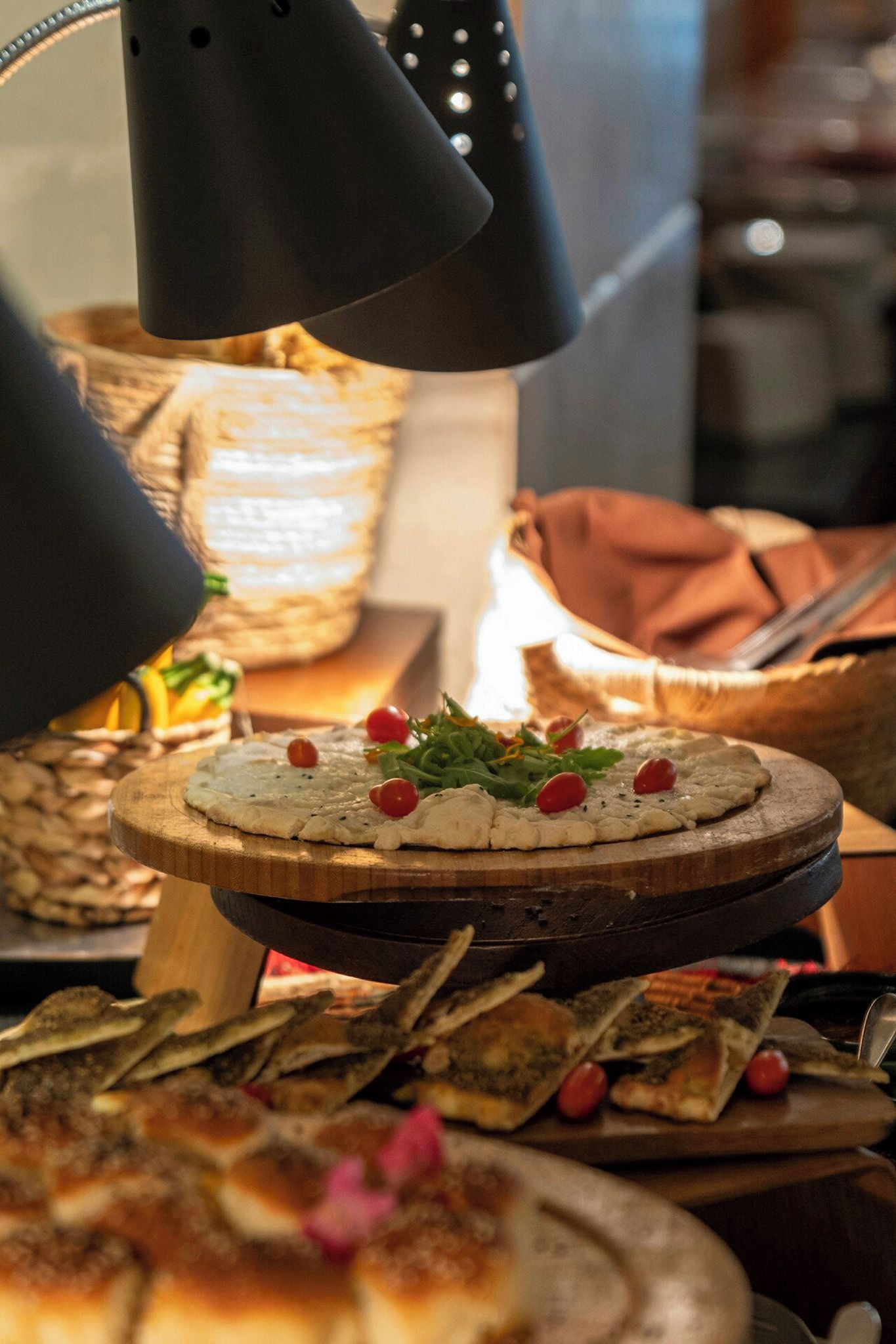 A food display with various dishes, including a round platter with a white spread and red berries, under a spotlight.