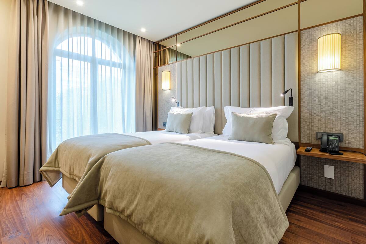 A hotel room with a large bed, a bedside table with a lamp, and a telephone.