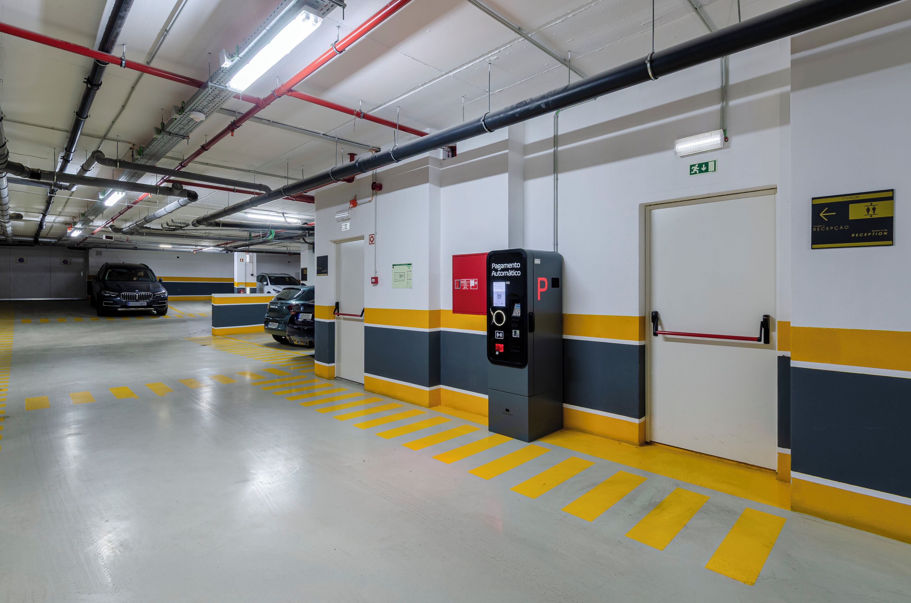 Een parkeergarage met aangegeven parkeerplaatsen, een receptie en een vluchtweg.