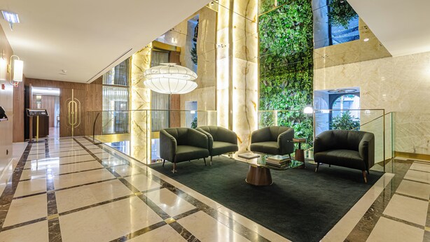 Un vestíbulo amplio con suelo a cuadros, dos sillones, una mesita de café y una pared cubierta de jardín vertical.
