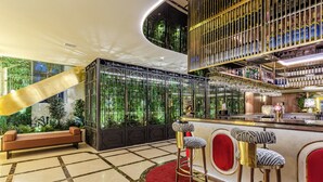 Un área de bar con alfombra roja, un banco y una pared vegetal cubierta con vidrio.