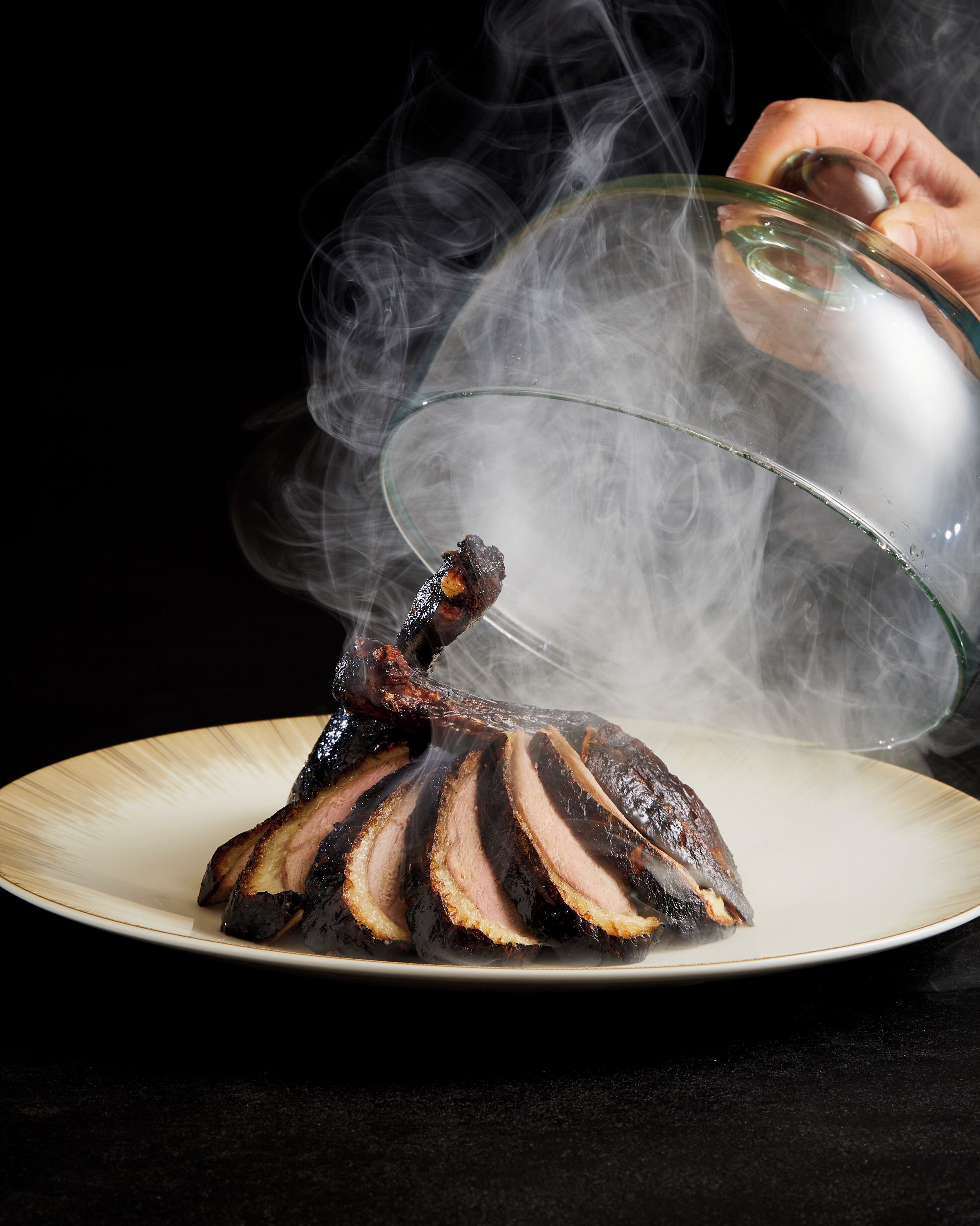 Un canard rôti, présenté sur une assiette, dont la vapeur s'élève.